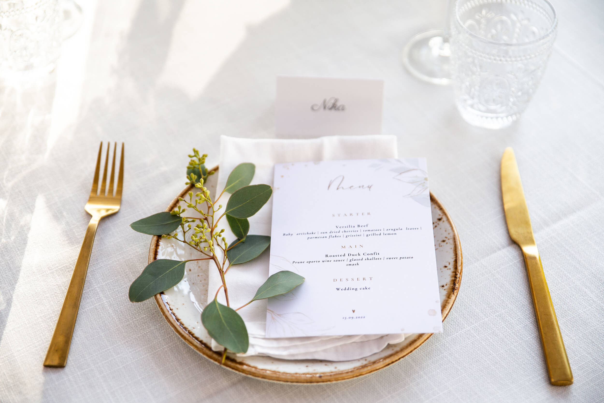 a table place laid out with cutlery, glasses, name tag and menu laid in the centre of the plate. A decorative piece of mistletoe is placed next to the menu
