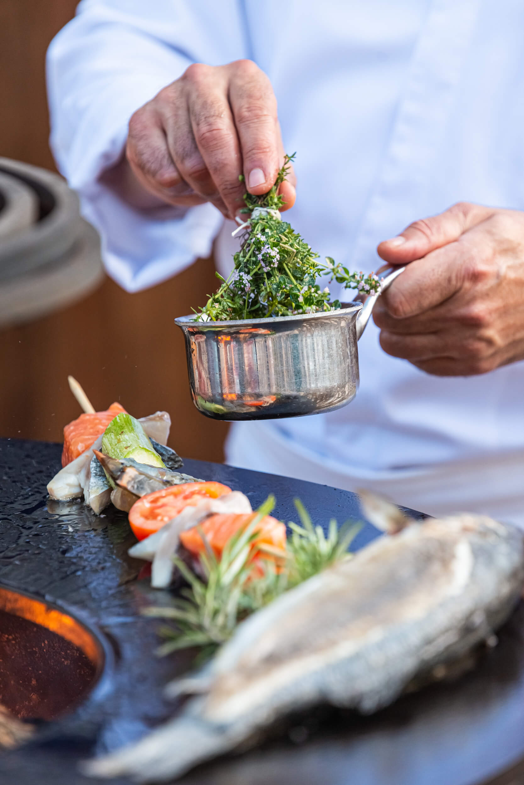 A chef adding garnish to his freshly cooked fish dish