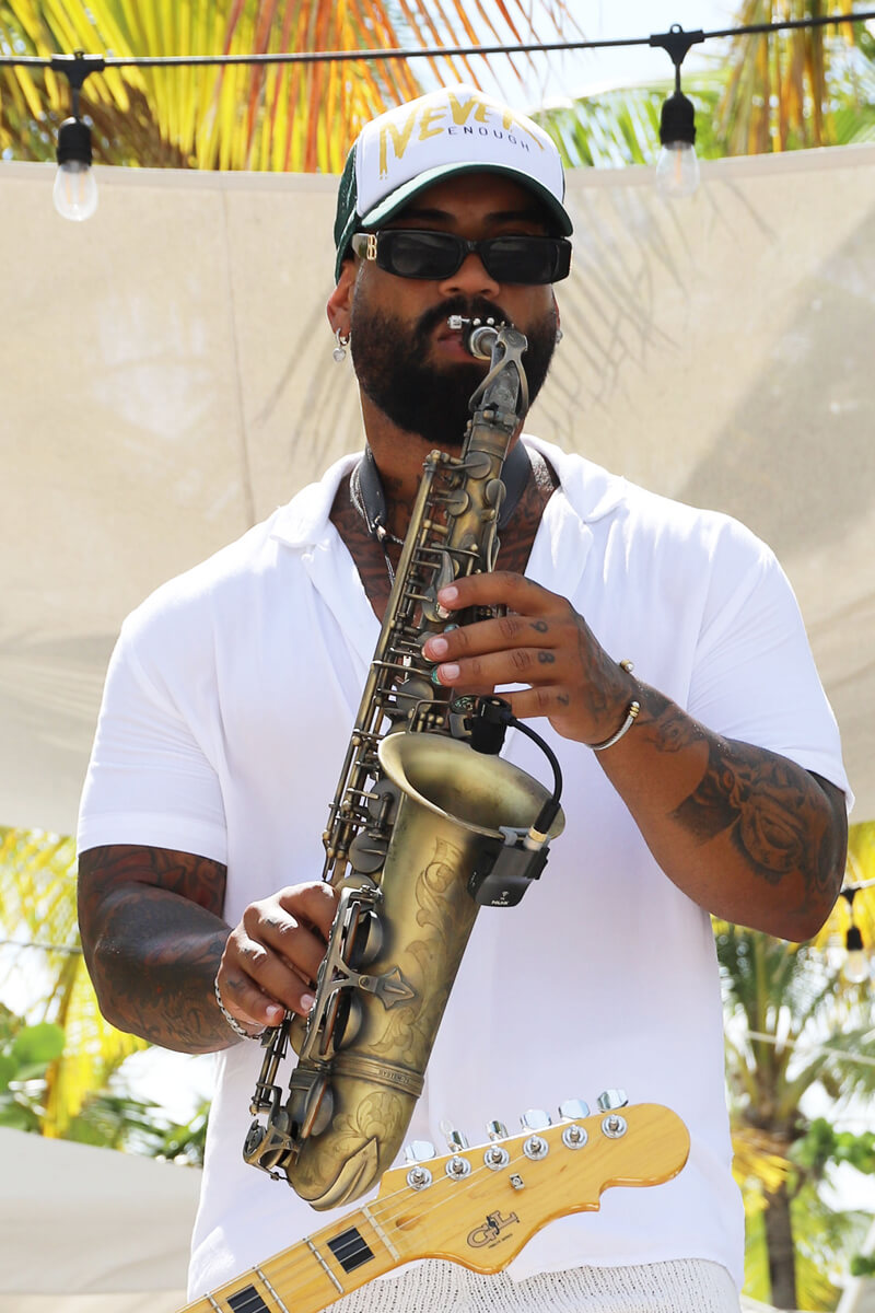 A man playing the Saxophone in front of palm trees